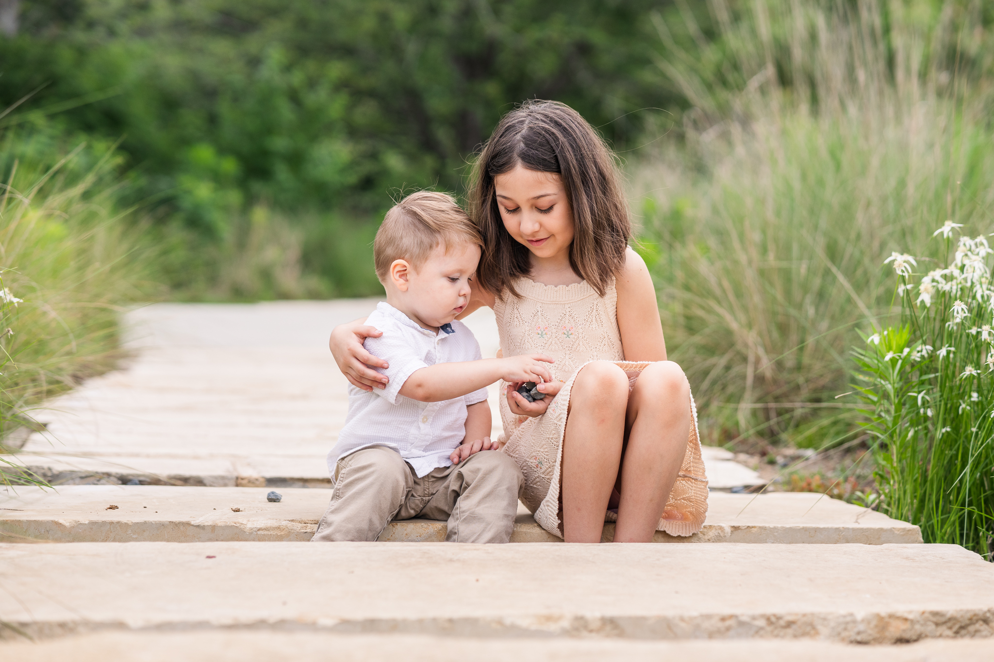 young girl and toddler boy absorbed in play in park setting