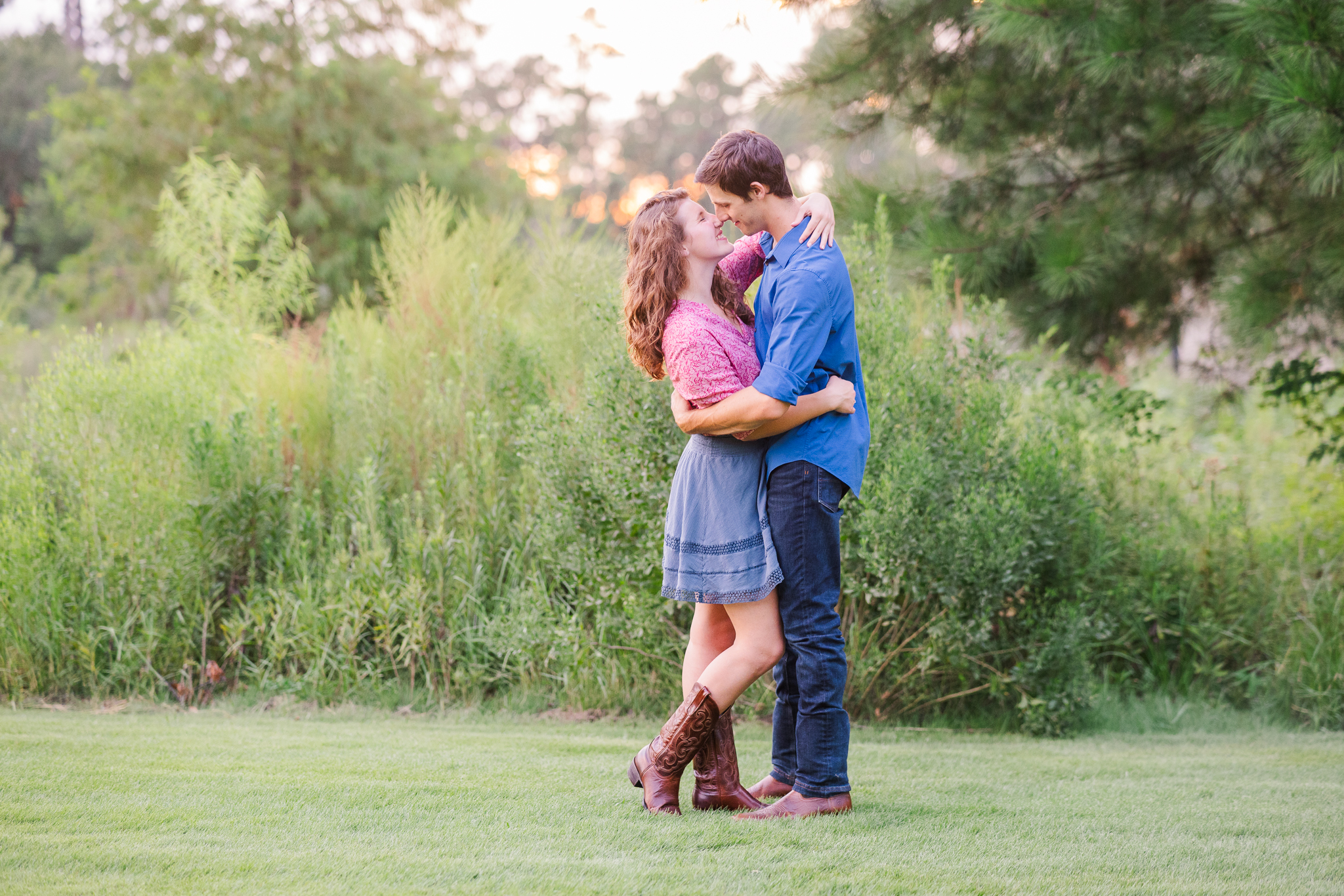 young couple facing one another in tall grasses with sunset glow