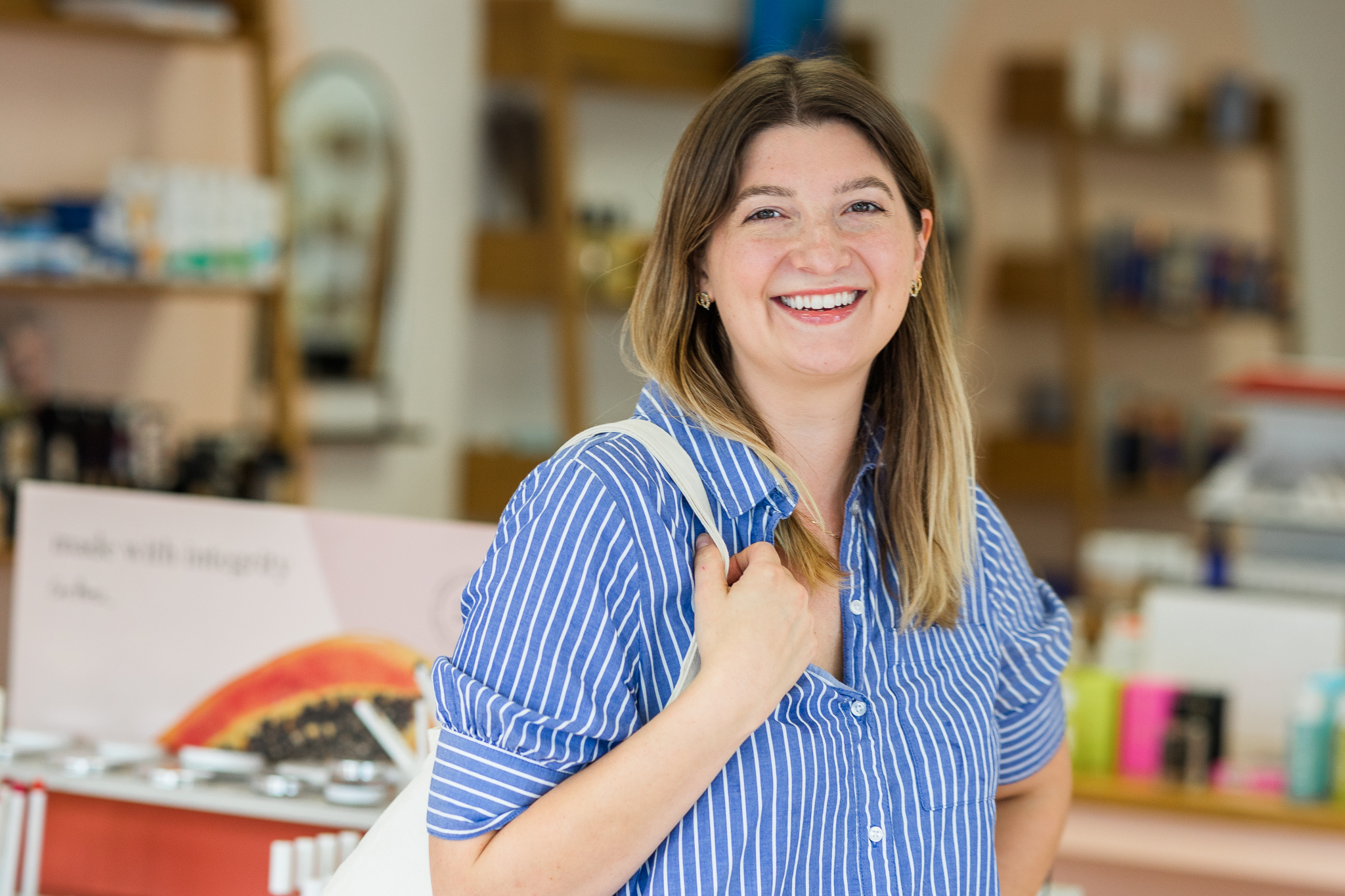 beauty shop owner in blue shirt dress holding shopping tote