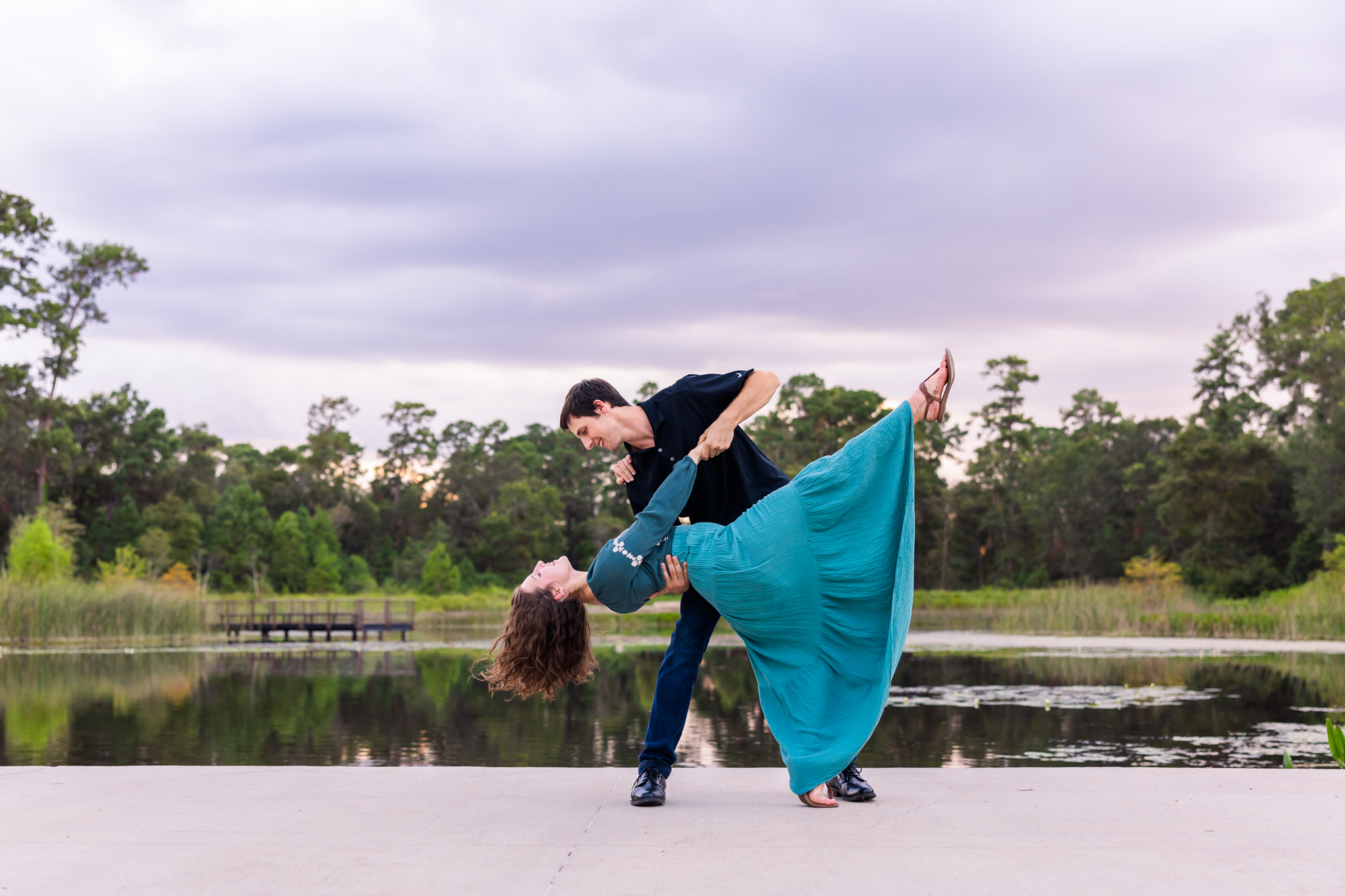 young couple in casual clothes doing a dip under a cloudy blue sky